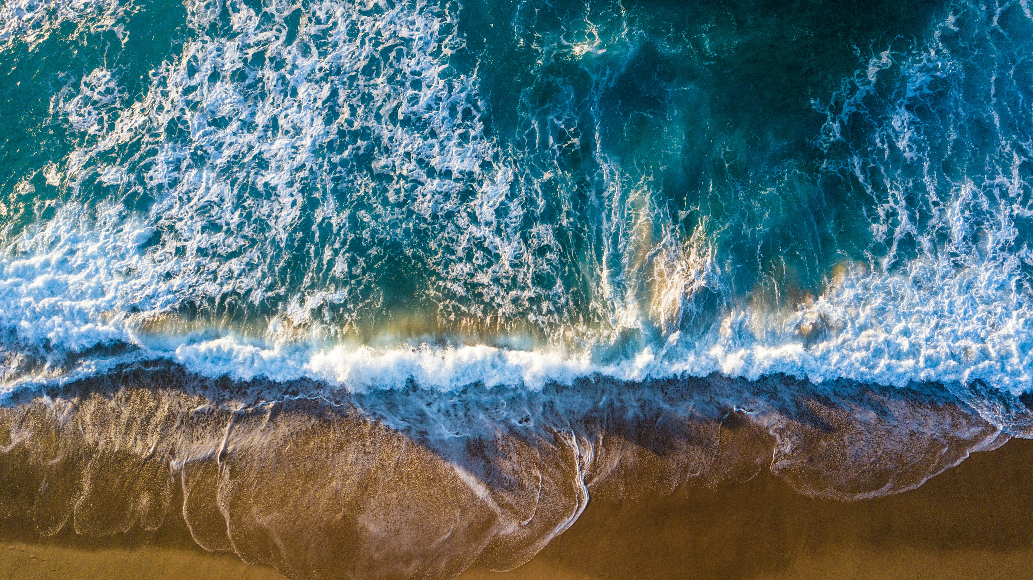 greenish blue ocean waves hitting the shore at the beach