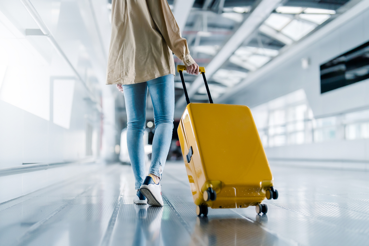 woman walking in airport with suitcase